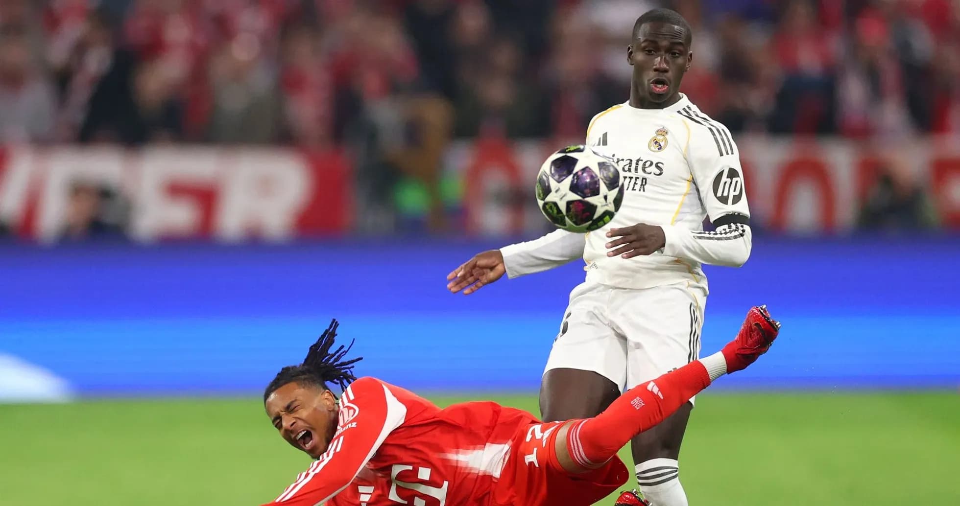 Jugador de Real Madrid controlando el balón mientras rival cae