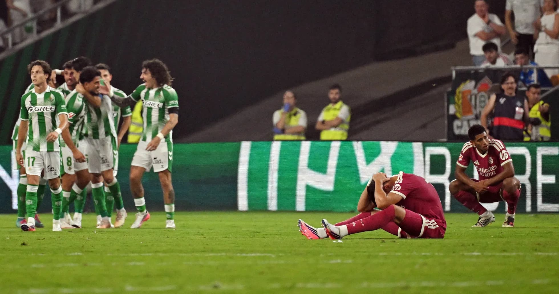 Jugadores de Betis celebrando tras un gol, rival decepcionado