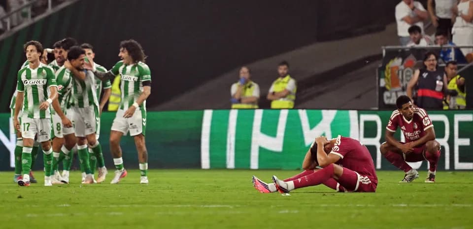 Jugadores de Betis celebrando tras un gol, rival decepcionado