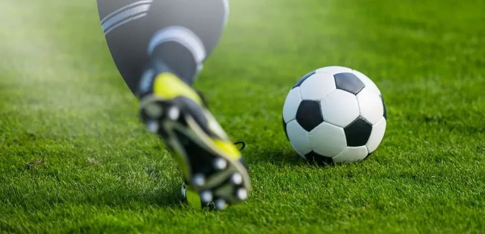 Jugador pateando un balón de fútbol en campo