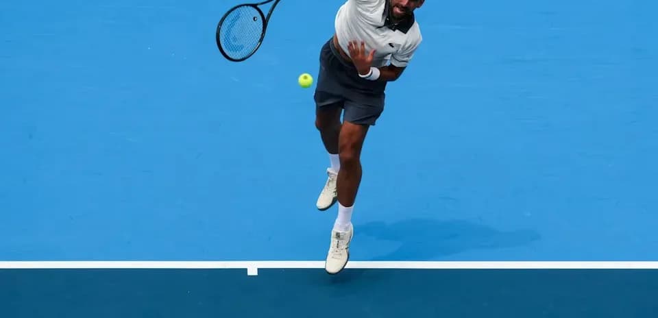 Jugador de tenis realizando un saque en la cancha