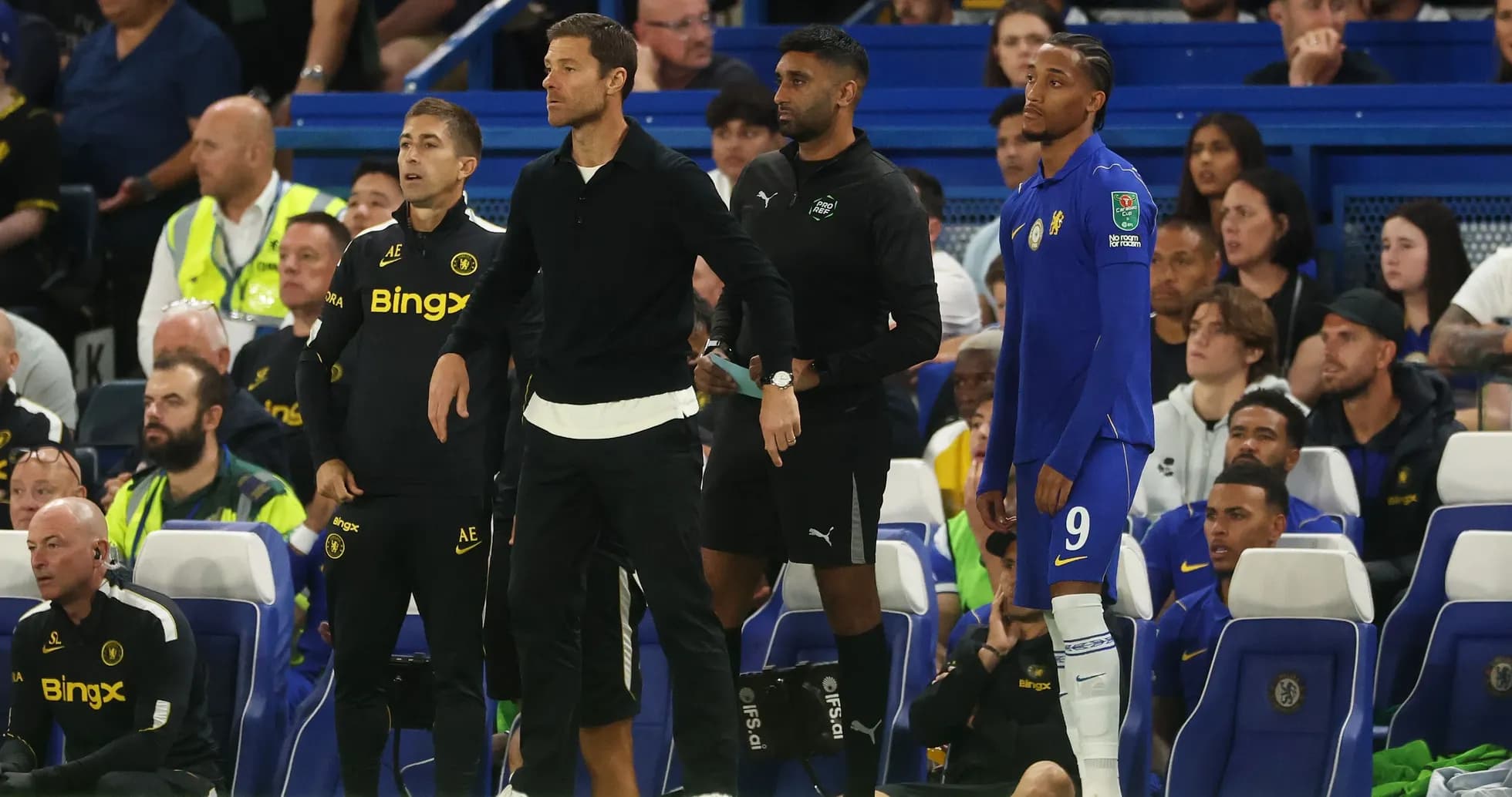 Entrenadores y jugador esperando en la línea de banda