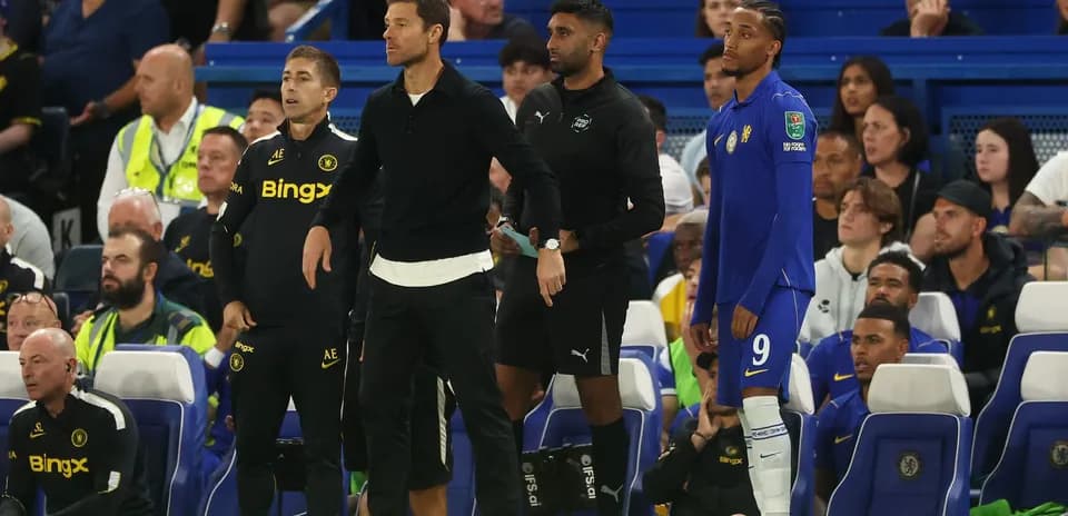 Entrenadores y jugador esperando en la línea de banda