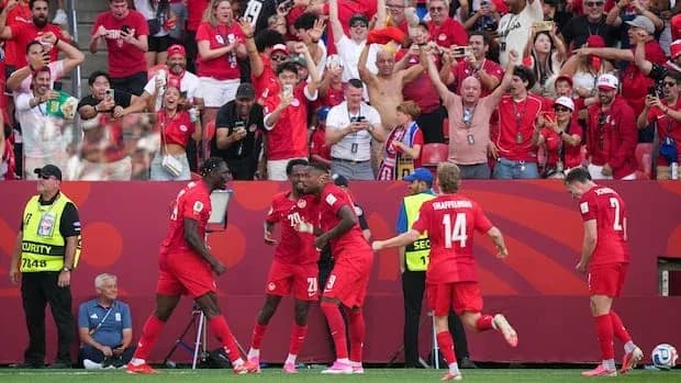 Jugadores celebrando un gol con aficionados en el fondo
