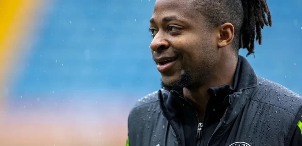 Jugador sonriente con chaqueta del Celtic FC en lluvia