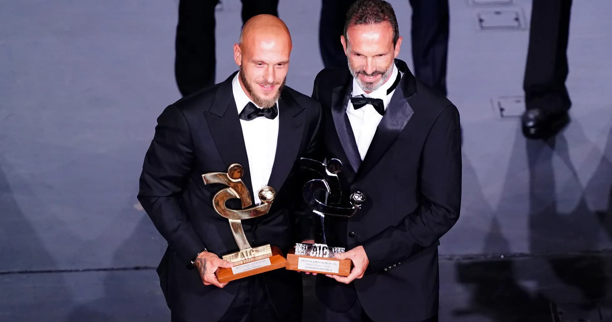 Dos jugadores sosteniendo trofeos en evento de premiación