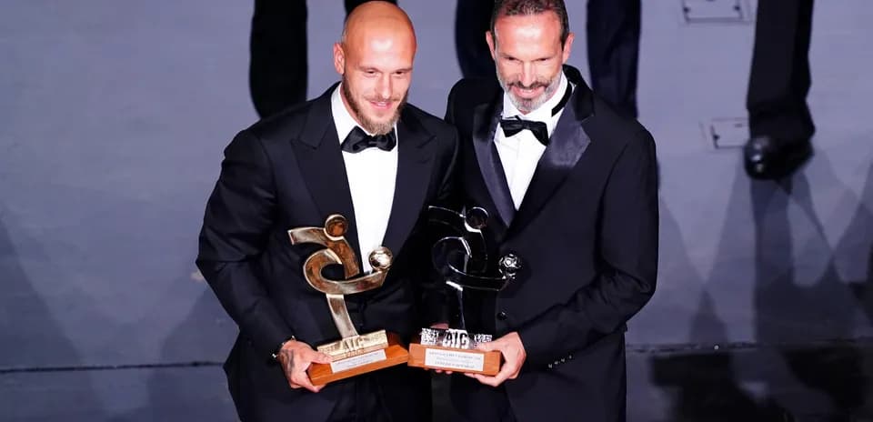 Dos jugadores sosteniendo trofeos en evento de premiación