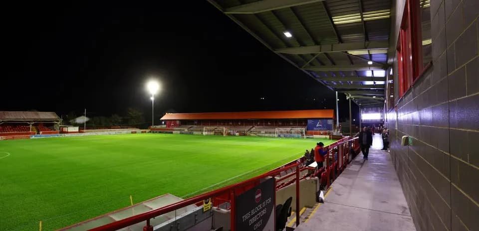 Estadio iluminado con césped verde y gradas vacías