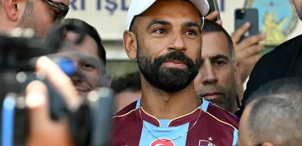 Jugador en camiseta de Trabzonspor rodeado de periodistas