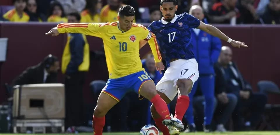 Jugador de Colombia intenta driblar a jugador francés