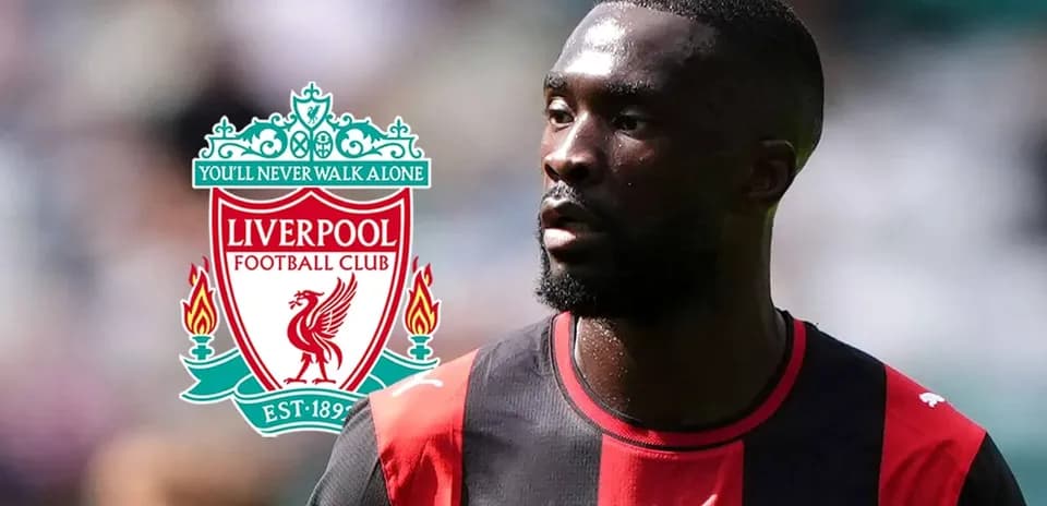 Jugador con camiseta negra y roja junto a logo de Liverpool