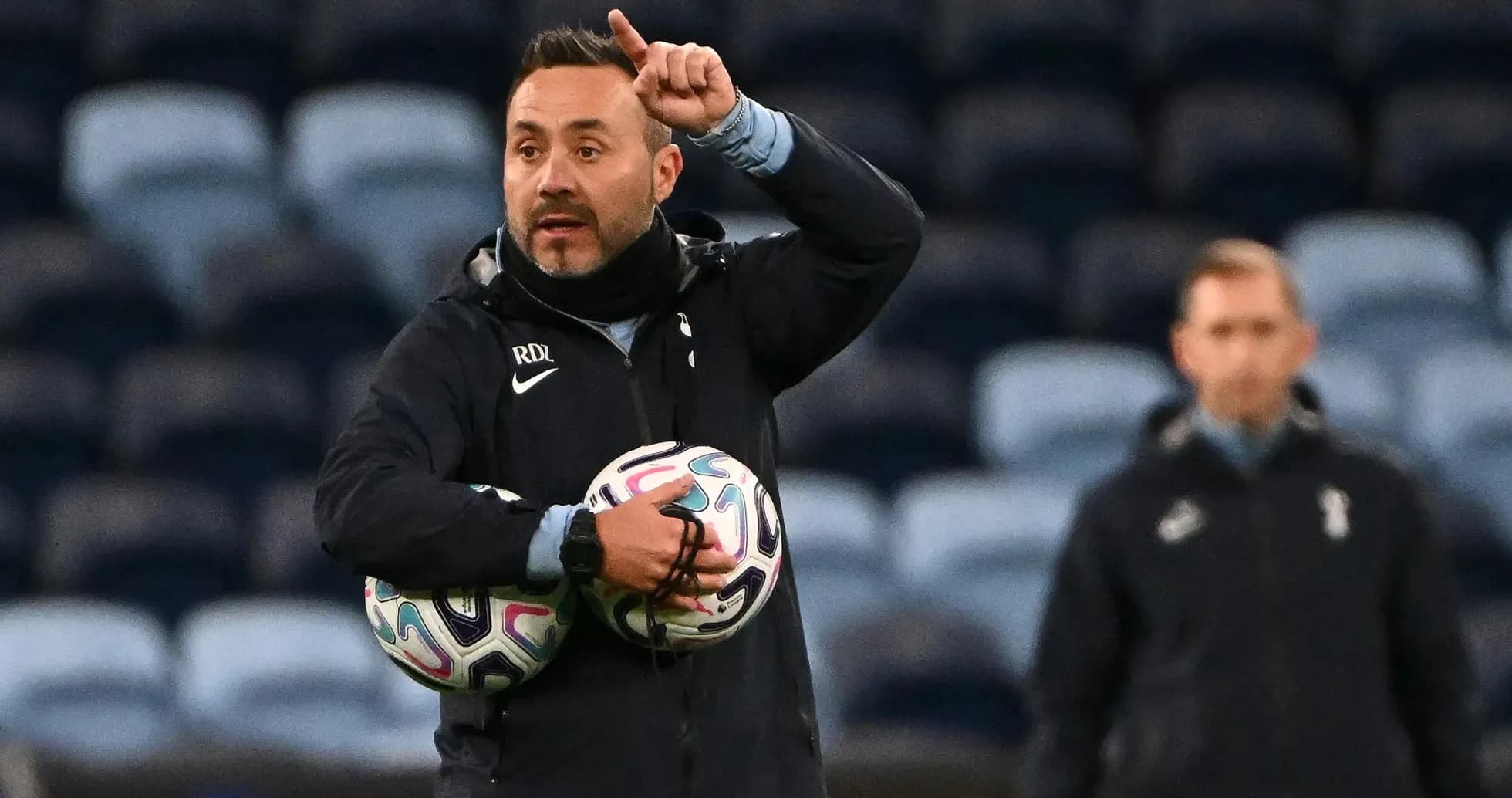 Entrenador dirigiendo instrucciones con balones en brazos