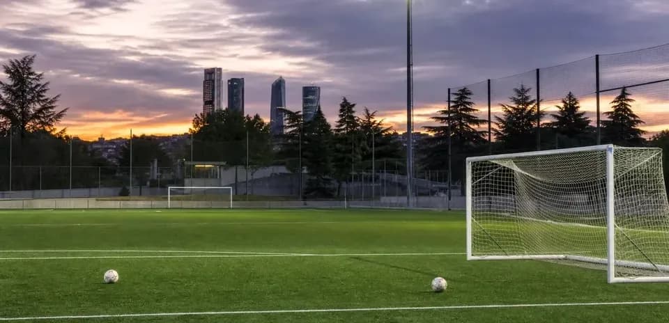 Campo de fútbol con balón y edificios al fondo