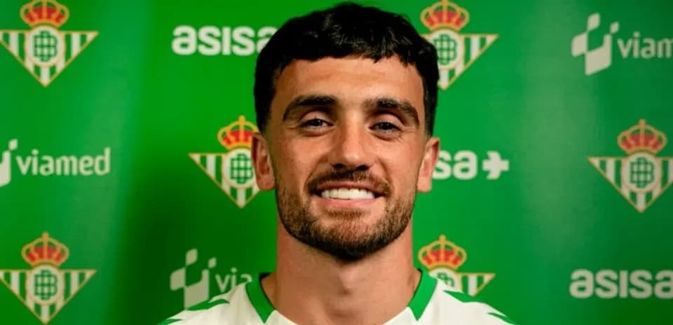 Jugador sonriente frente a fondo del Real Betis