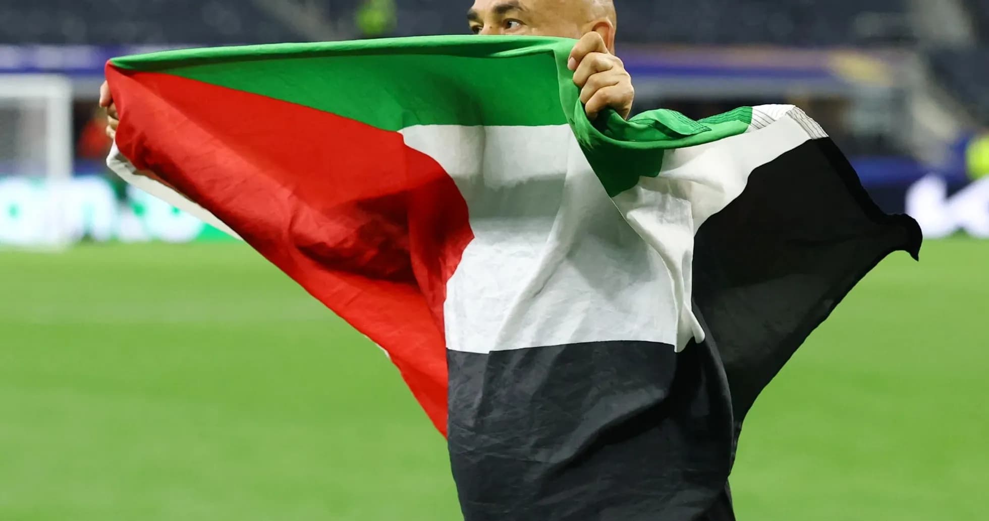 Hombre sosteniendo una bandera de Palestina en el campo