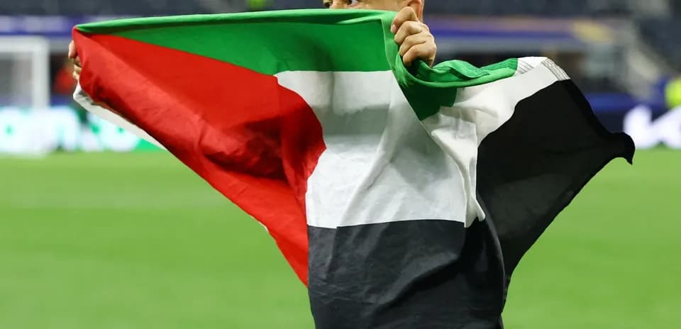 Hombre sosteniendo una bandera de Palestina en el campo