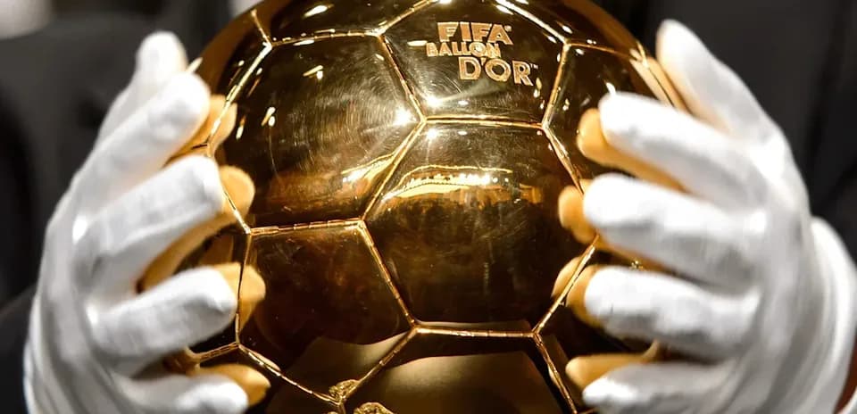 Trofeo Balón de Oro sostenido con guantes