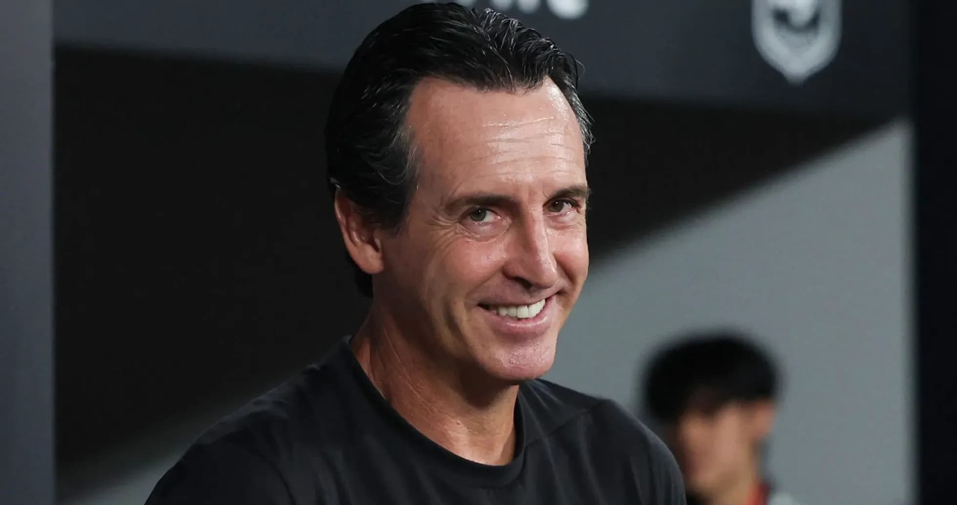 Entrenador sonriendo en el banquillo durante el partido