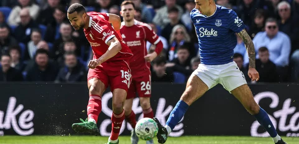 Jugador de Liverpool driblando mientras es marcado por rival