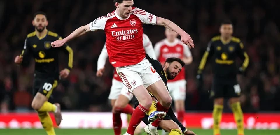 Jugador de Arsenal esquivando a oponente caído