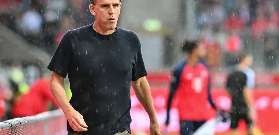 Entrenador caminando por la línea de banda en lluvia