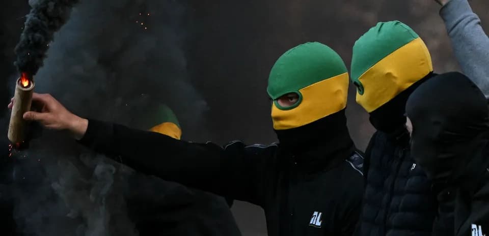 Person encapuchado sostiene un objeto incendiario