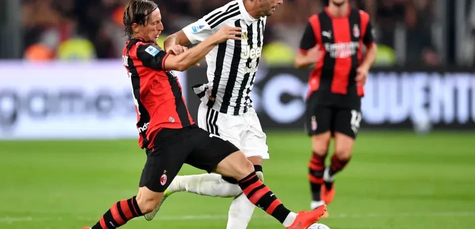 Jugador de AC Milan intentando quitar el balón a jugador de Juventus