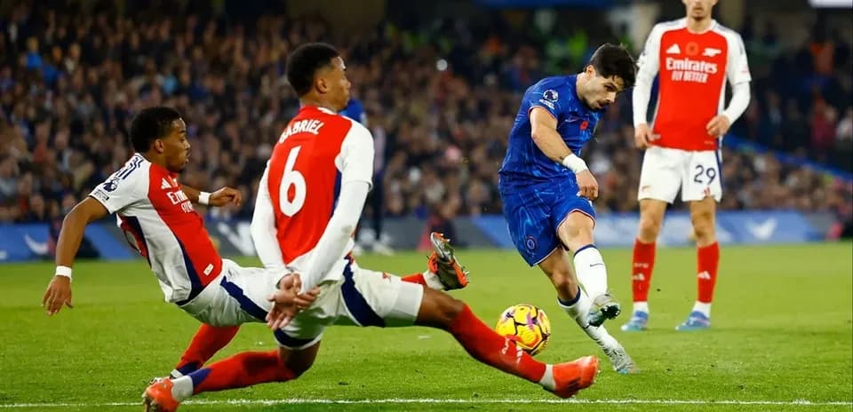Jugador de Chelsea disparando mientras dos defensores de Arsenal intentan interceptar