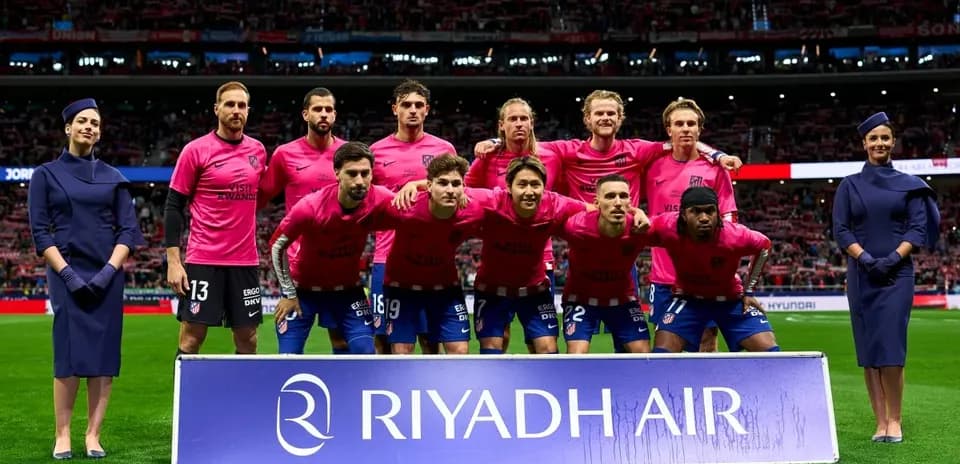 Equipo de fútbol posando con uniformes rosas en estadio