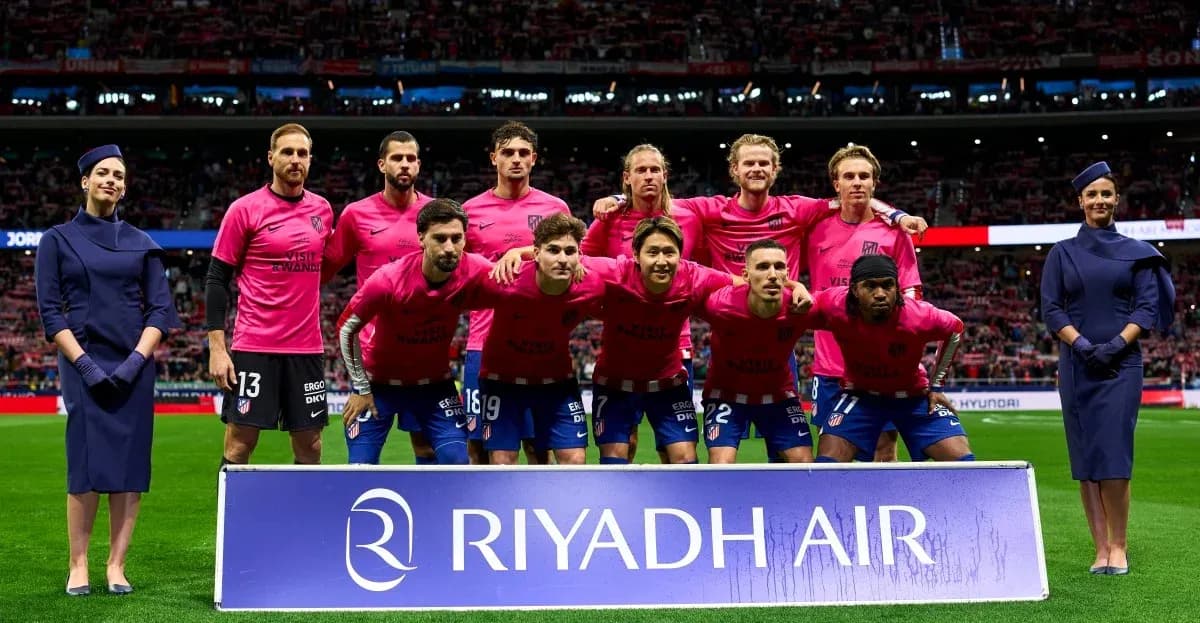 Equipo de fútbol posando con uniformes rosas en estadio