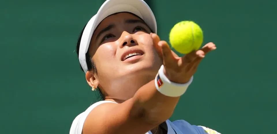 Jugadora lanzando la pelota de tenis al servicio