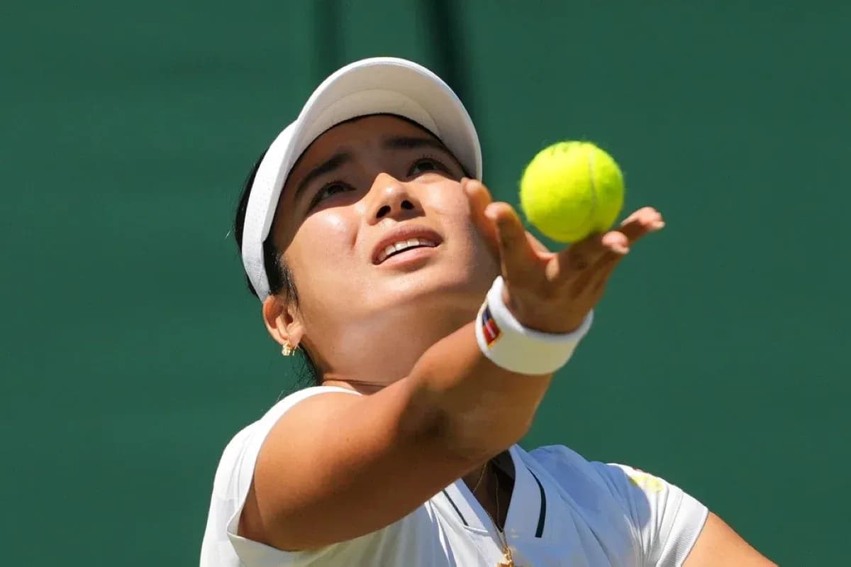 Jugadora lanzando la pelota de tenis al servicio