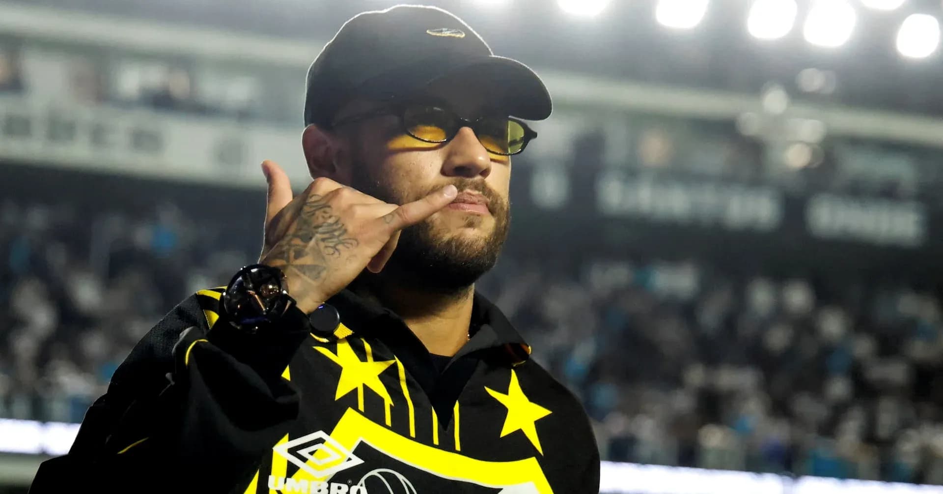 Hombre con gafas y gesto de llamada en estadio
