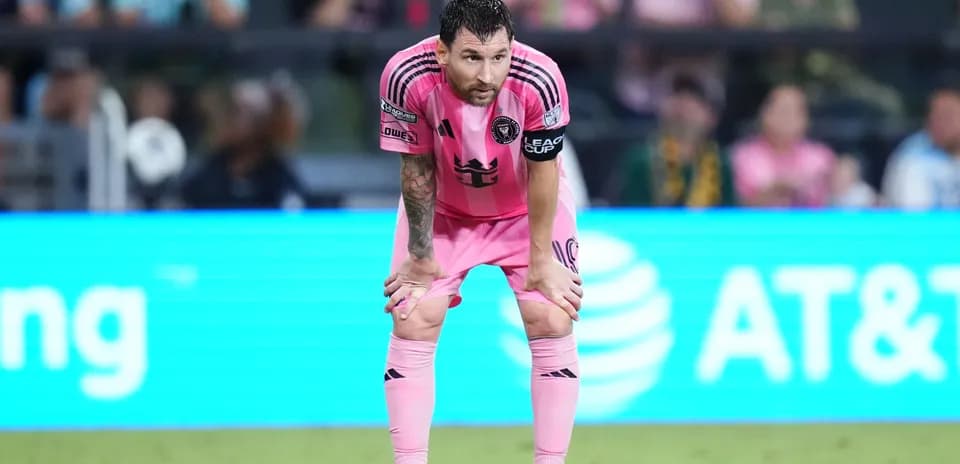 Jugador con camiseta rosa descansando en el campo
