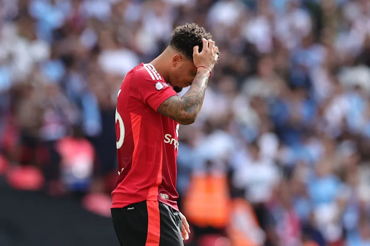 Jugador con camiseta roja sosteniendo su cabeza en el campo