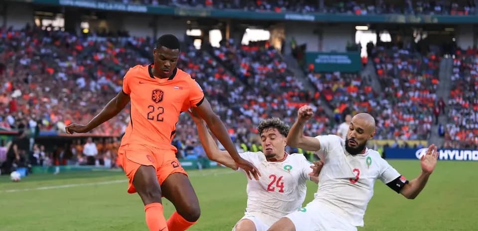 Jugador de Países Bajos superando a dos defensores marroquíes