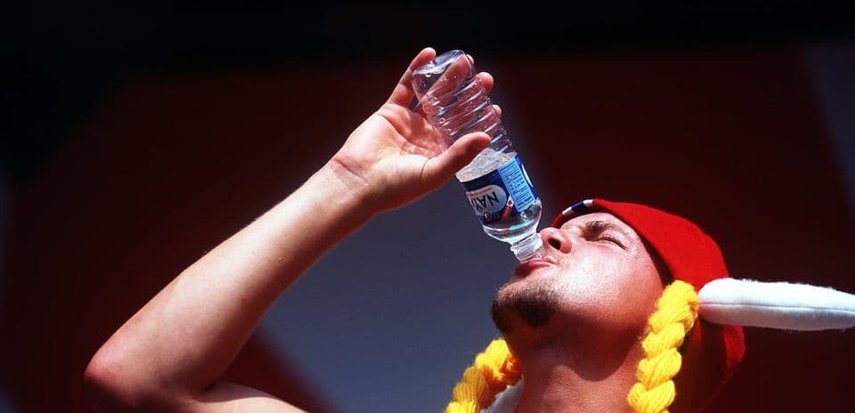 Hombre bebiendo agua de botella con gorro rojo