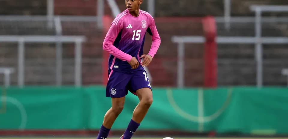 Jugador de fútbol entrenando con camiseta morada y rosa