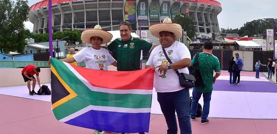 Aficionados sosteniendo bandera de Sudáfrica en estadio