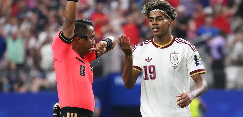 Árbitro mostrando tarjeta y jugador de España discutiendo