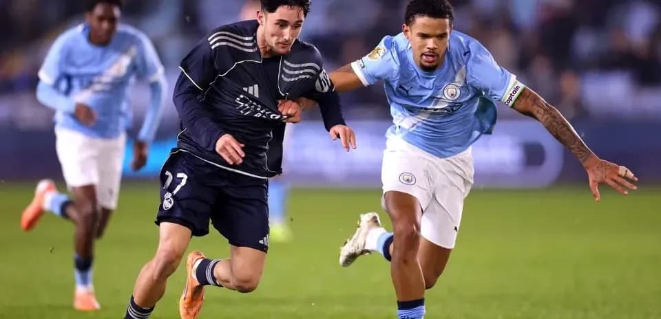 Jugador de Real Madrid corriendo con balón, perseguido por jugador de Manchester City
