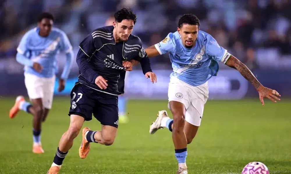 Jugador de Real Madrid corriendo con balón, perseguido por jugador de Manchester City