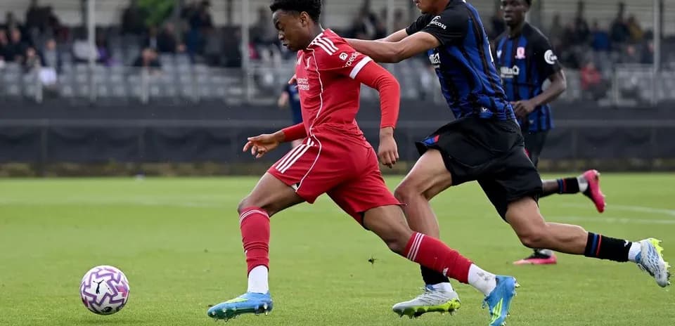 Jugador con camiseta roja corriendo hacia el balón