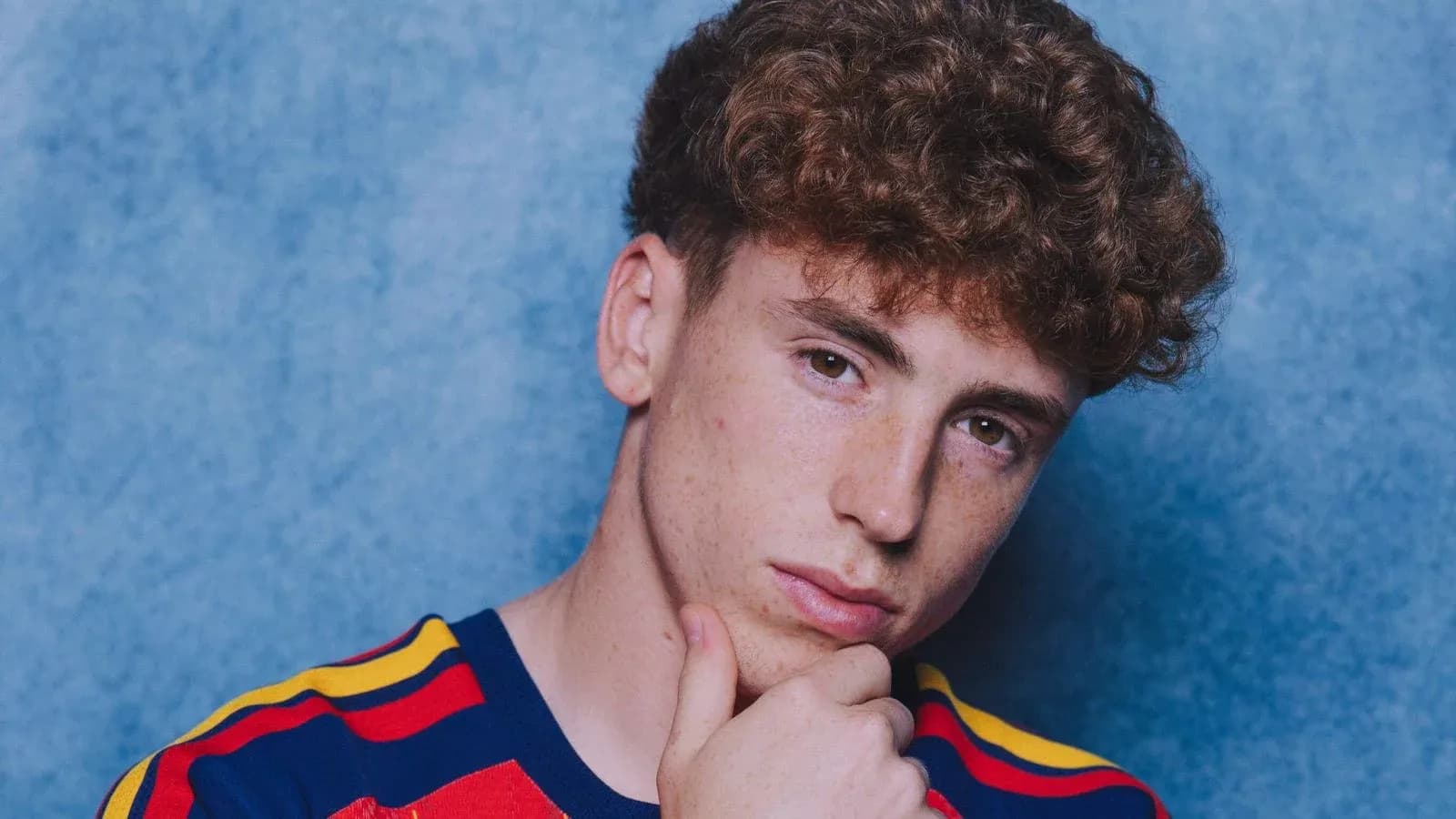 Joven con camiseta a rayas frente a fondo azul