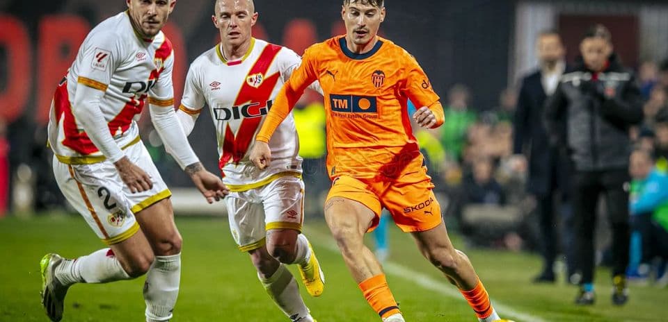 Jugador de Valencia esquivando a defensores de Rayo Vallecano