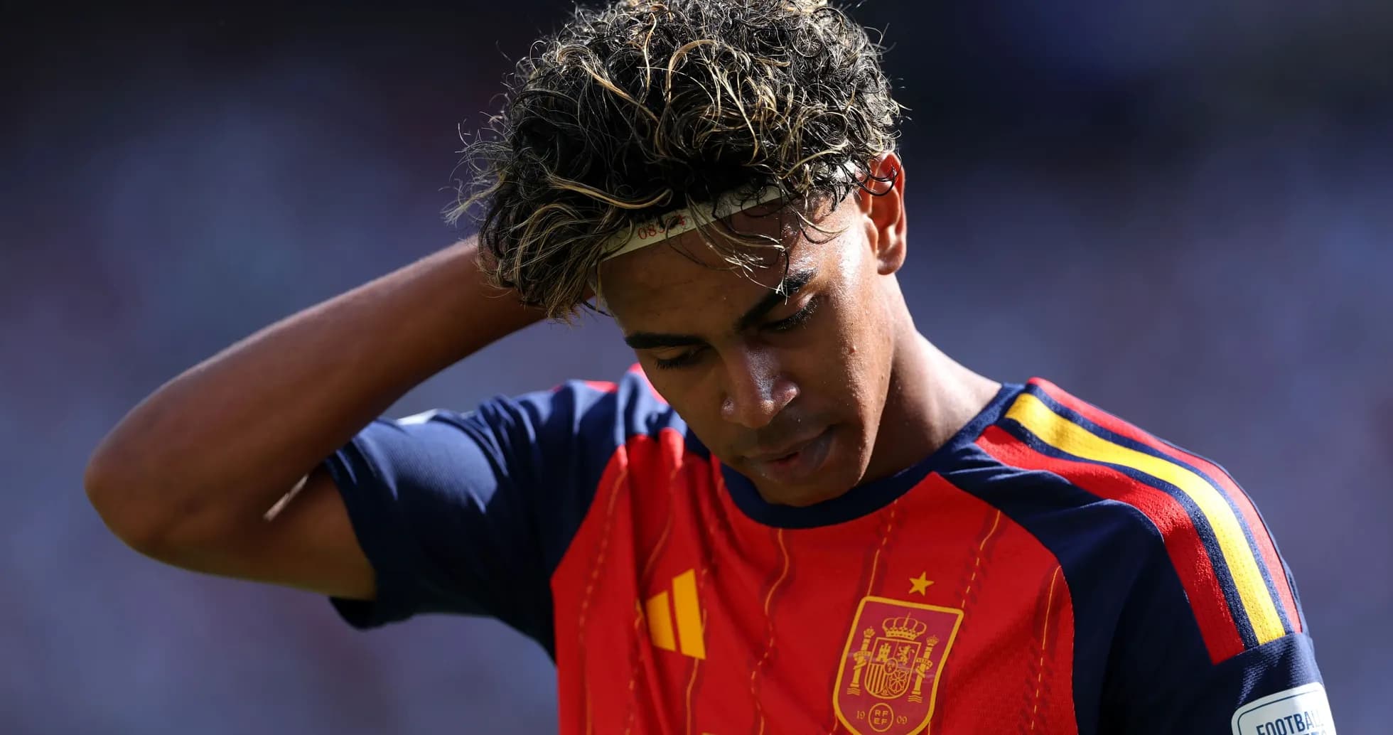 Jugador de España con camiseta roja, pensativo en el campo