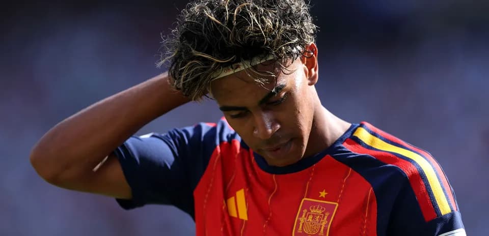 Jugador de España con camiseta roja, pensativo en el campo