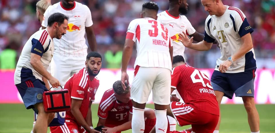 Jugadores de Bayern y Leipzig rodeando a un jugador caído