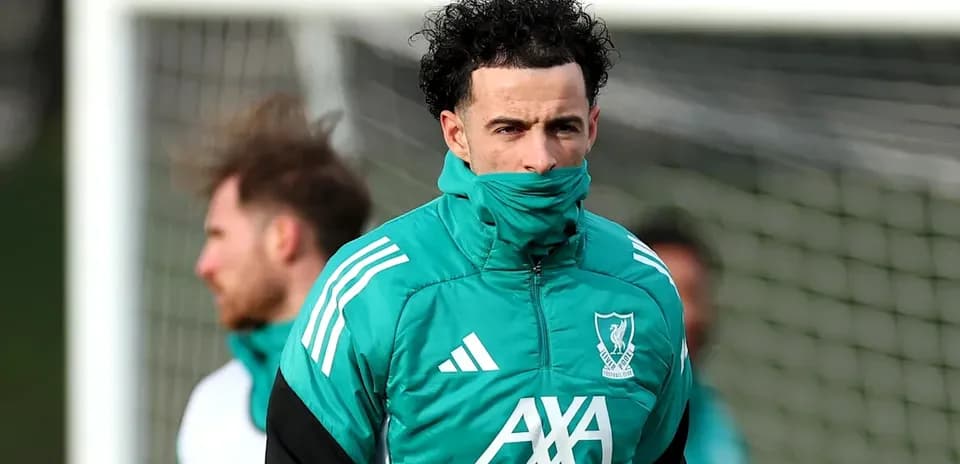 Jugador de Liverpool entrenando con abrigo en el campo