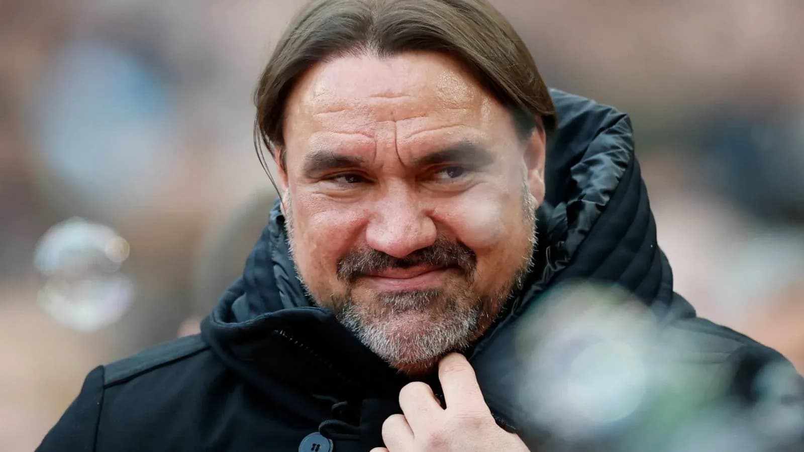 Entrenador con abrigo negro en el estadio